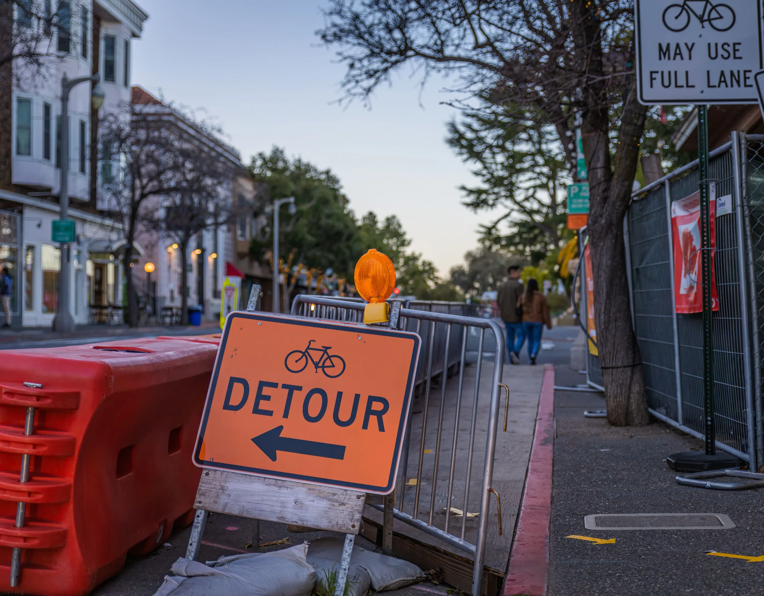 Orange vinyl banner mounted on a construction fence at a street event